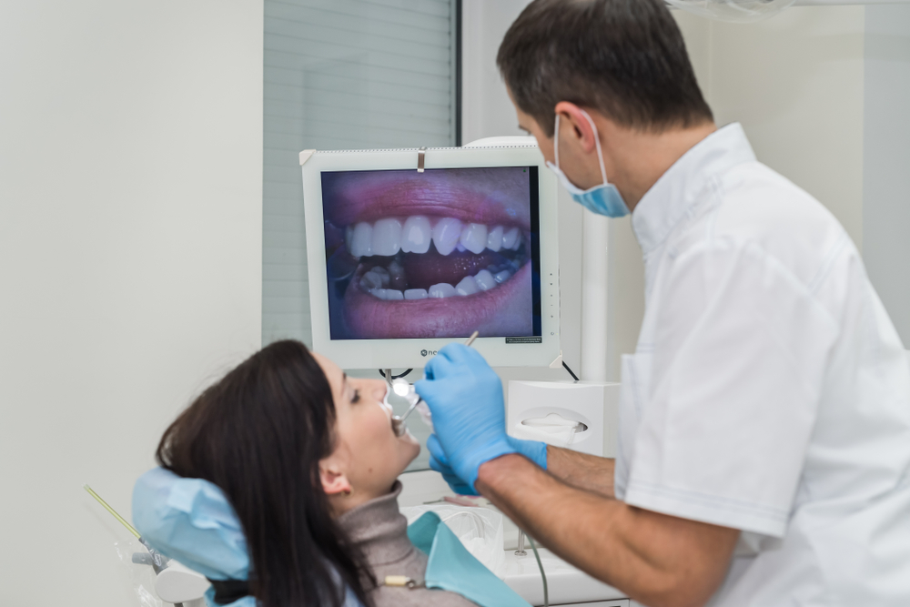 dentist using intraoral camera on female patient's teeth